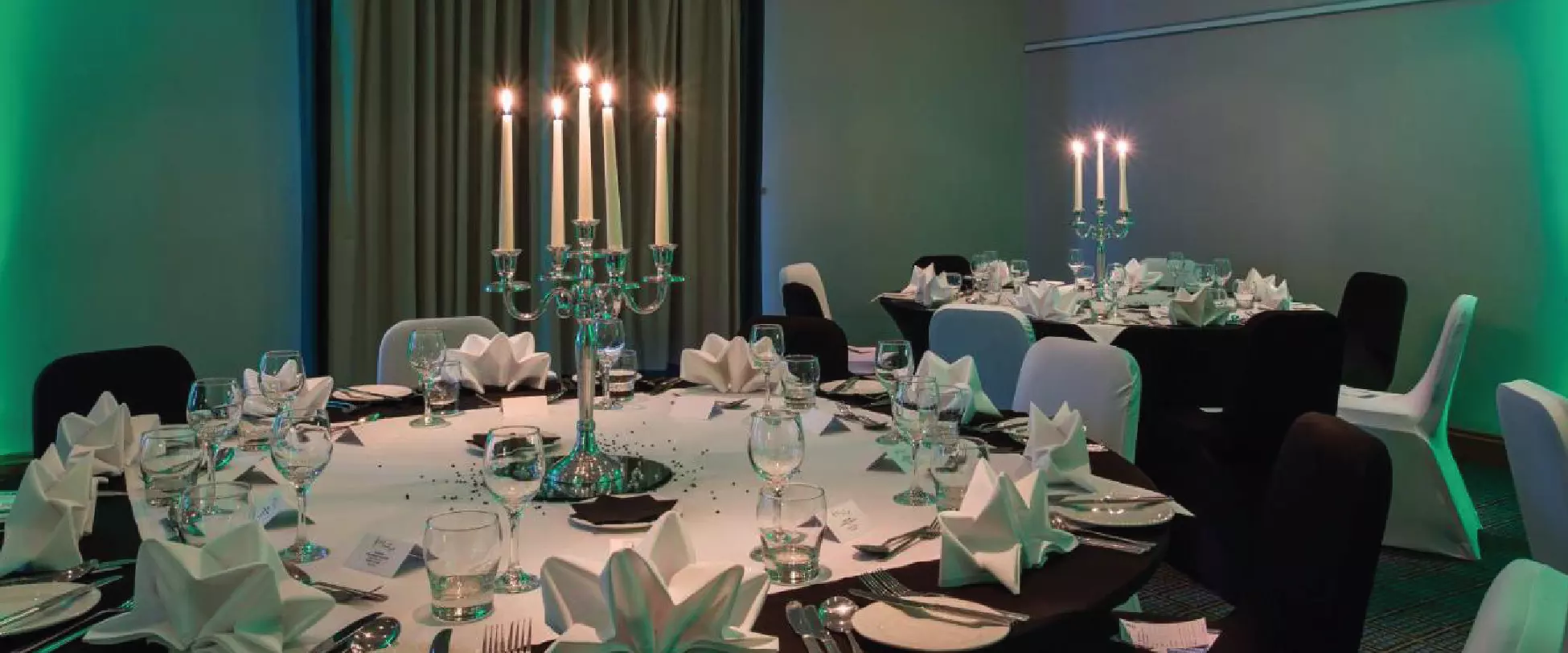 Tables set up for a wedding with large silver candlesticks..